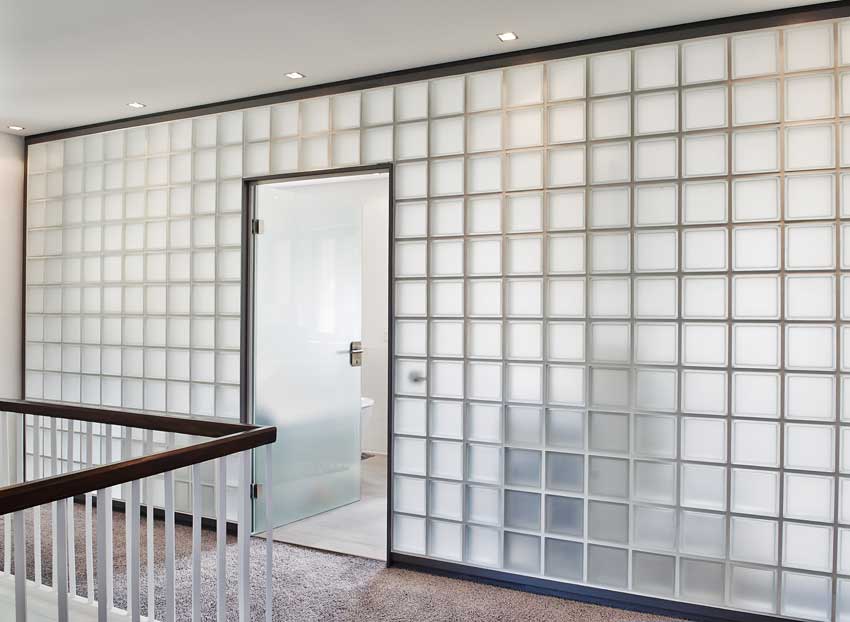 Grande parete con porta centrale realizzata con vetromattoni trasparenti.