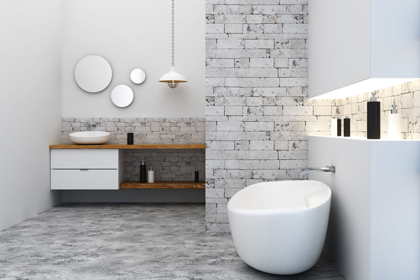 bagno moderno con rivestimento effetto pietra, vasca design e mobili in legno massello.