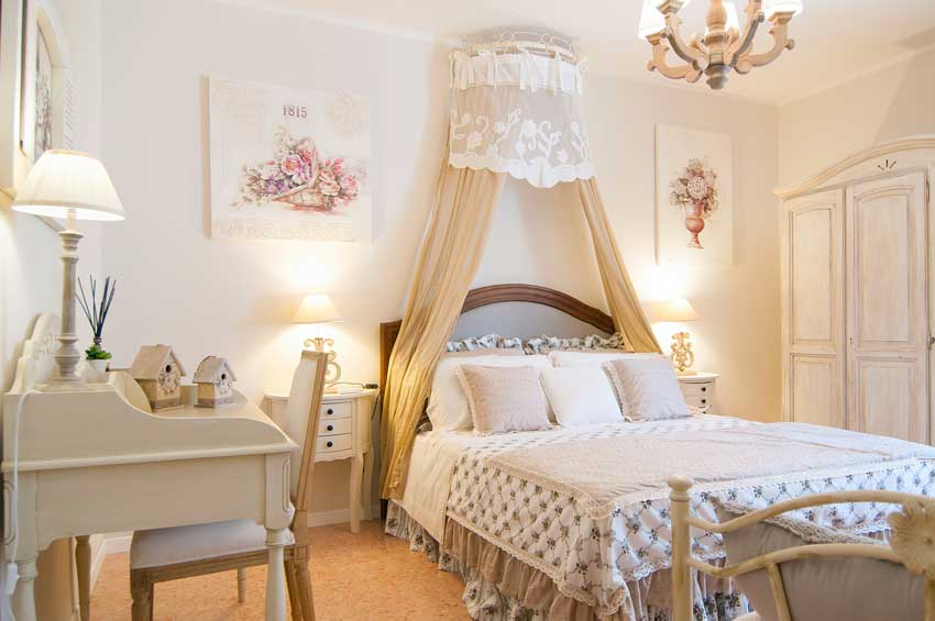 camera con arredamento shabby chic, letto con tende beige.