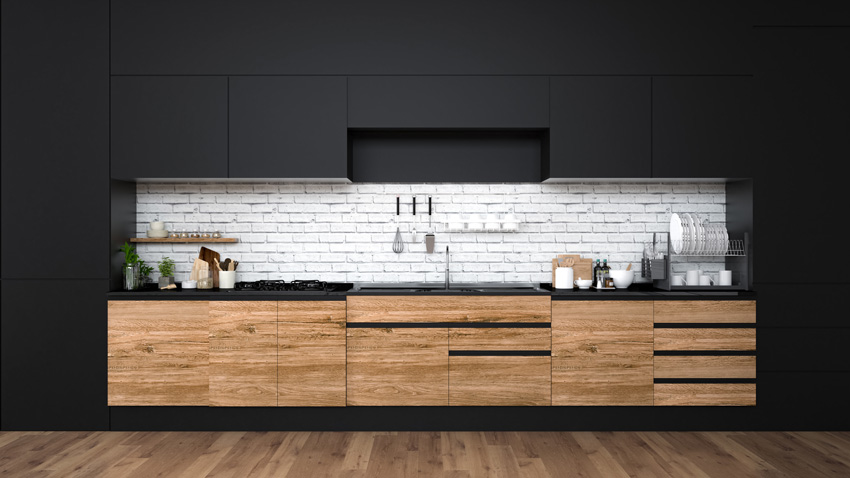 bella cucina nera spezzata con paraschizzi effetto mattoni bianchi e mobili in legno.