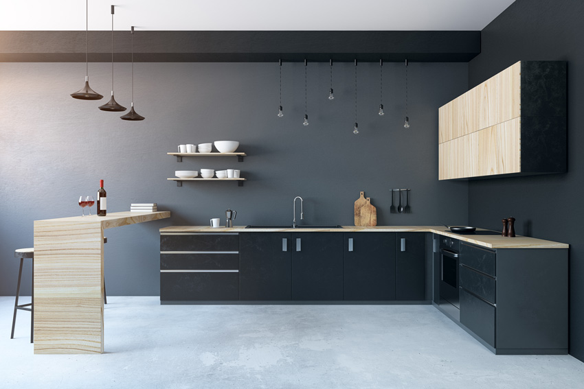 cucina moderna nera con pensili, top e penisola in legno, belle le lampadine sospese.