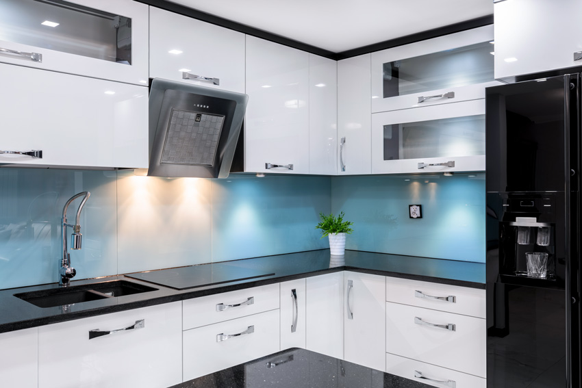 cucina dal design moderno di colore bianca lucido, spezzata con paraschizzi azzurri e top nero.