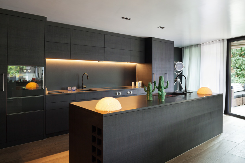 Cucina nera moderna con isola centrale e illuminazione design.