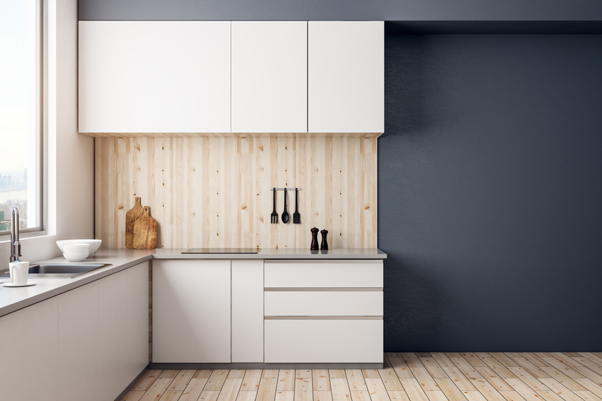 Una cucina moderna di piccola dimensione bianca con paraschizzi effetto legno chiaro.