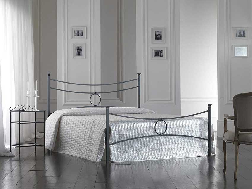 Letto in ferro battuto dal design moderno, pareti con boiserie bianca.