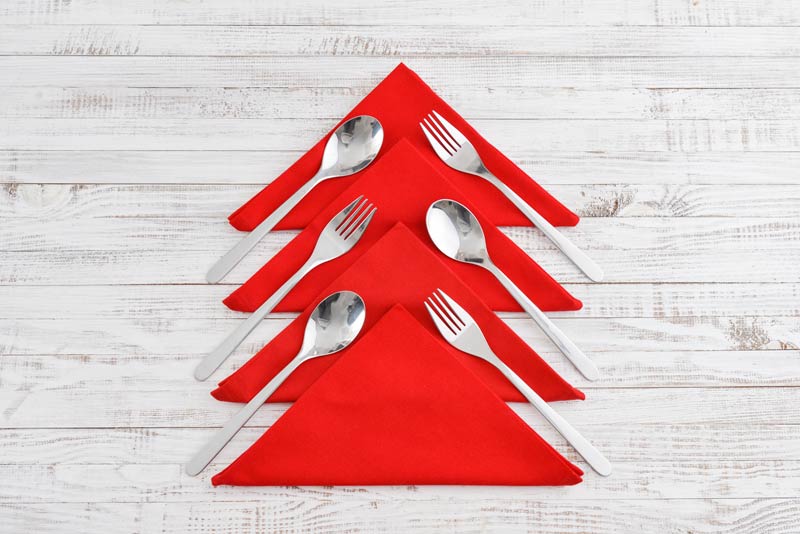 Tovaglioli rossi piegati a forma di albero di Natale per decorare la tavola.