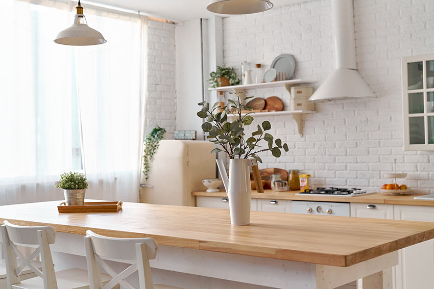 Una bella cucina bianca e legno dallo stile country, splendida la parete in mattoni a vista bianchi.