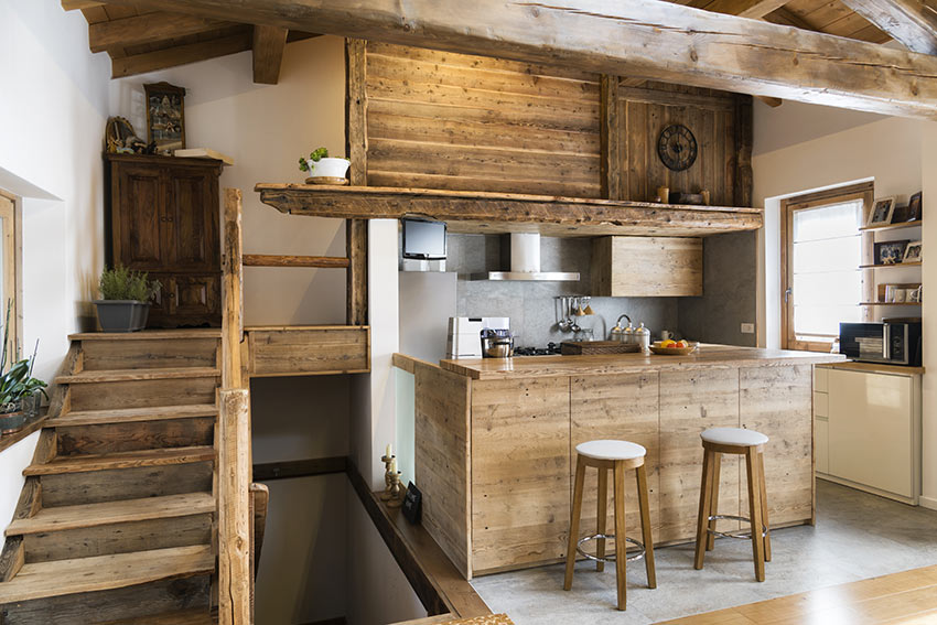 Bellissima cucina in legno grezzo con isola centrale e sgabelli.