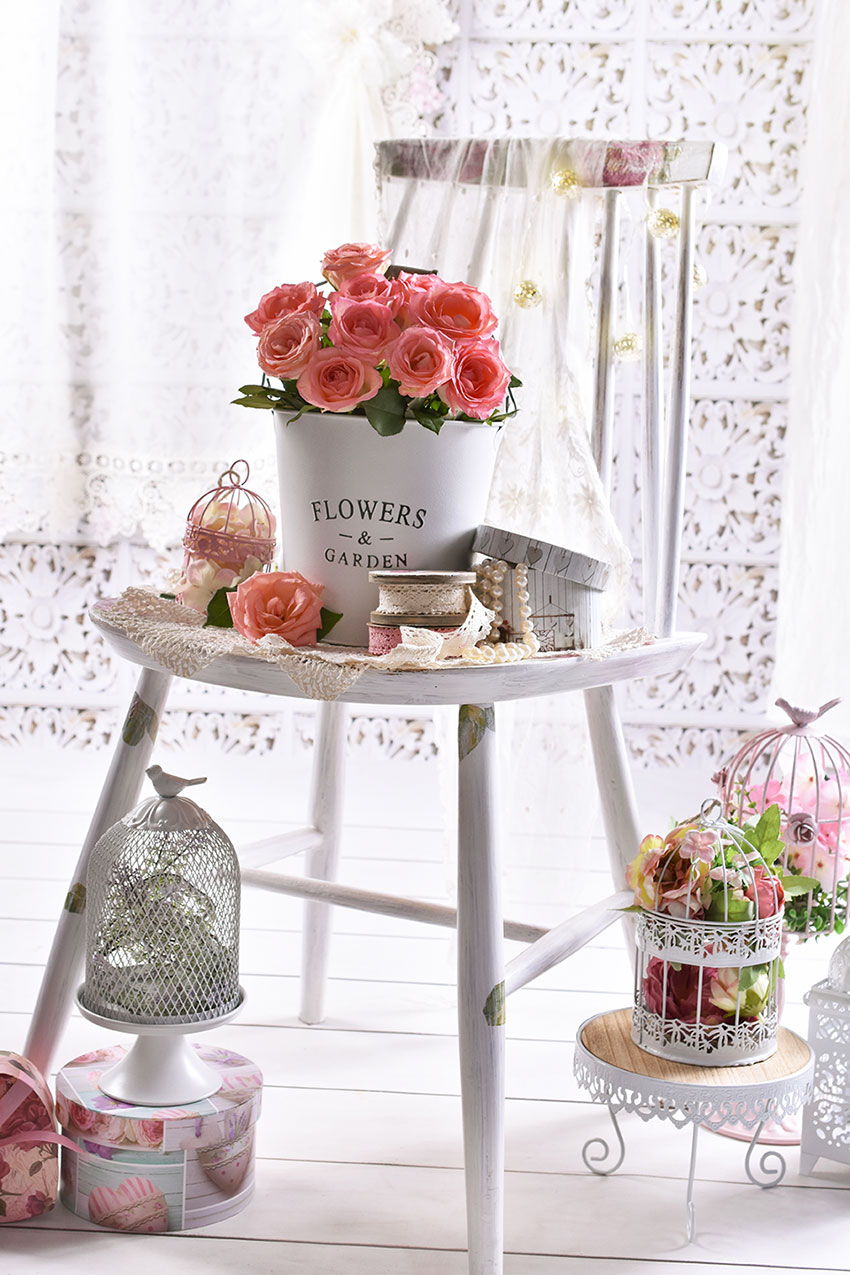 Un bel vaso bianco shabby con rose sopra una sgabello bianco