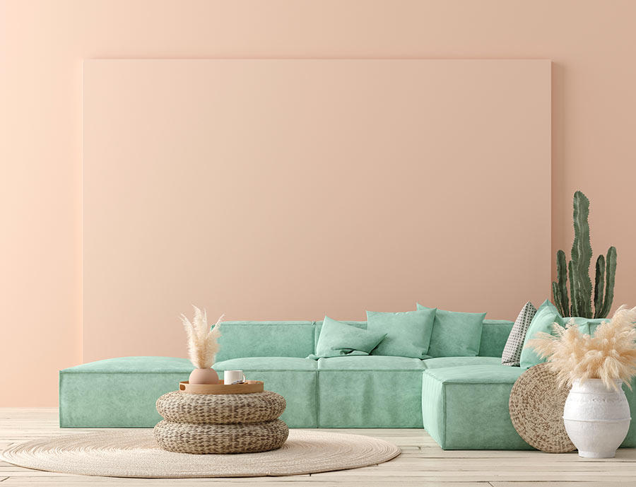 Salotto moderno con parete rosa e divano ad angolo verde acqua, cactus dietro al divano.