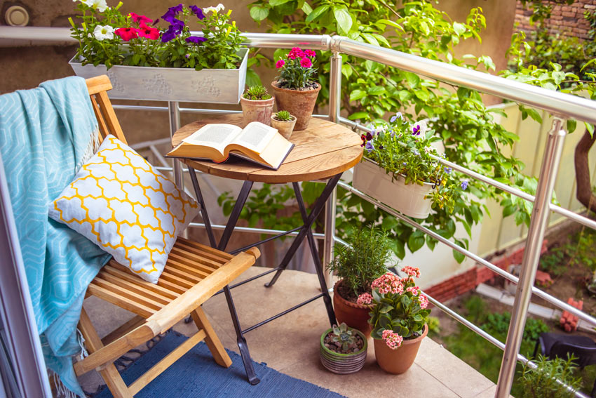 Balcone con tavolino tondo, un angolo lettura circondato di fiori.