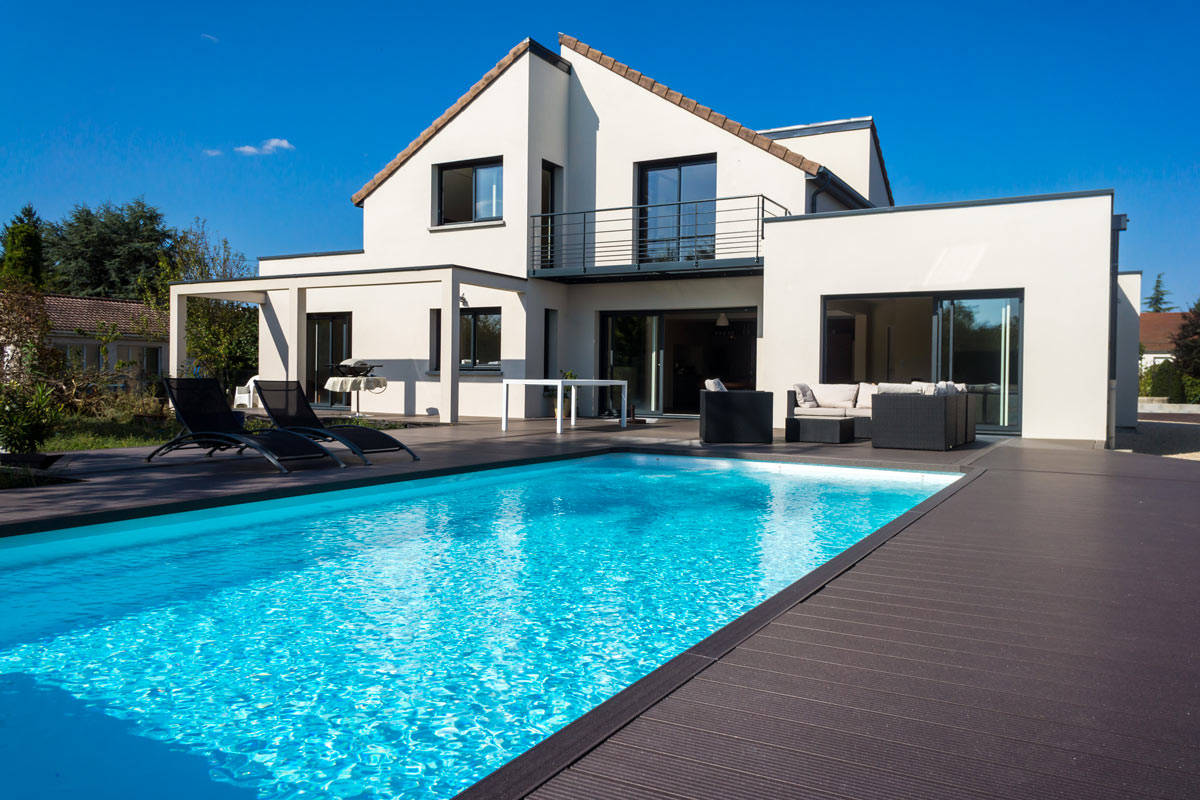 Bella casa con piscina rettangolare. Bordo piscina in legno scuro.