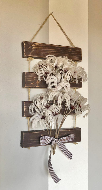 Decorazione fai da te da parete stile rustico con pallet e fiori secchi.