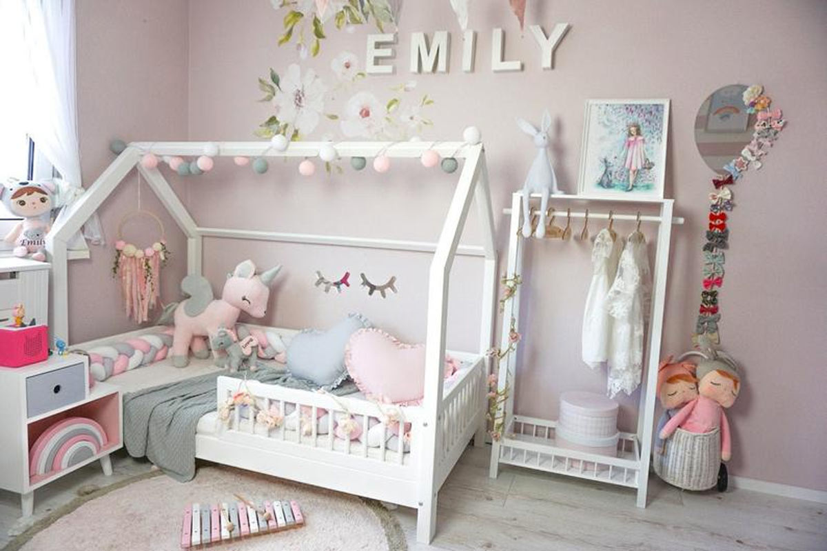 Bellissima cameretta per bambini con letto bianco e pareti rosa.