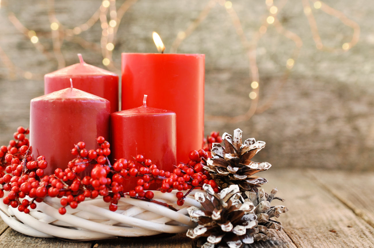 Candele rosse in un cestino bianco decorato con le bacche.