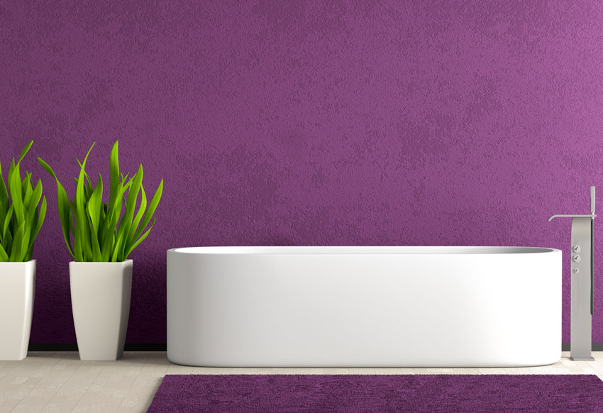 Bagno con vasca bianca davanti ad una parete color malva.