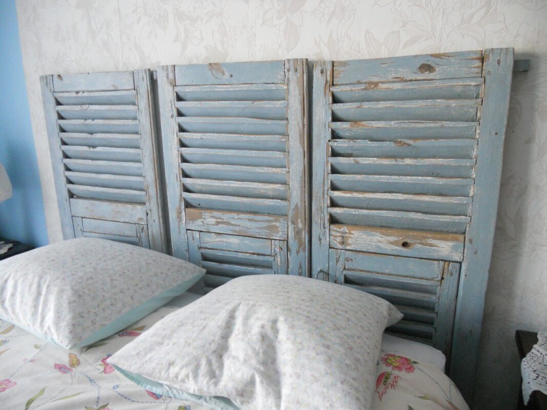 Testata letto shabby con vecchie persiane di colore azzurro.
