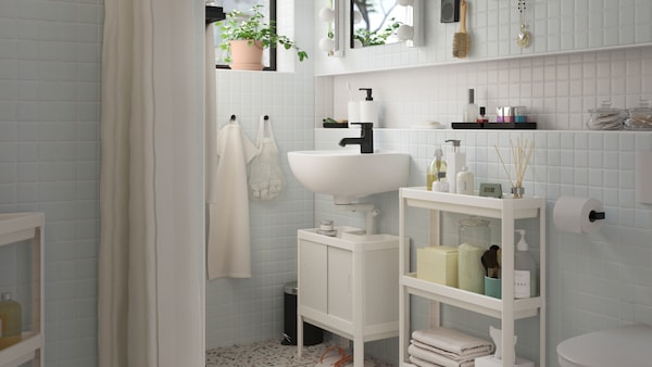 Set di mobili per bagno LILLTJÄRN/SKATSJÖN bianchi con miscelatore per lavabo SALJEN, vicino a un carrello VESKEN bianco con prodotti per l’igiene personale – IKEA