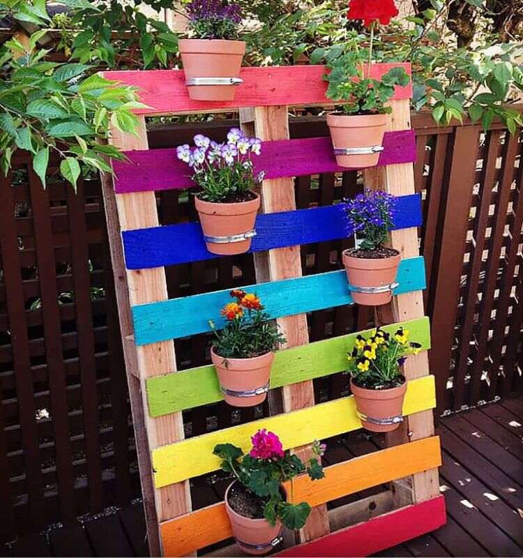 fioriera fai da te con pallet con colori dell'arcobaleno e vasi di fiori