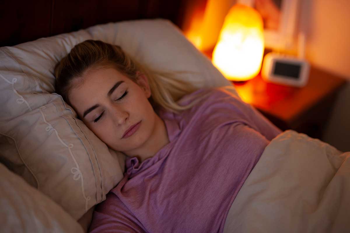 Donna che dorme con lampada di sale accesa in camera da letto.