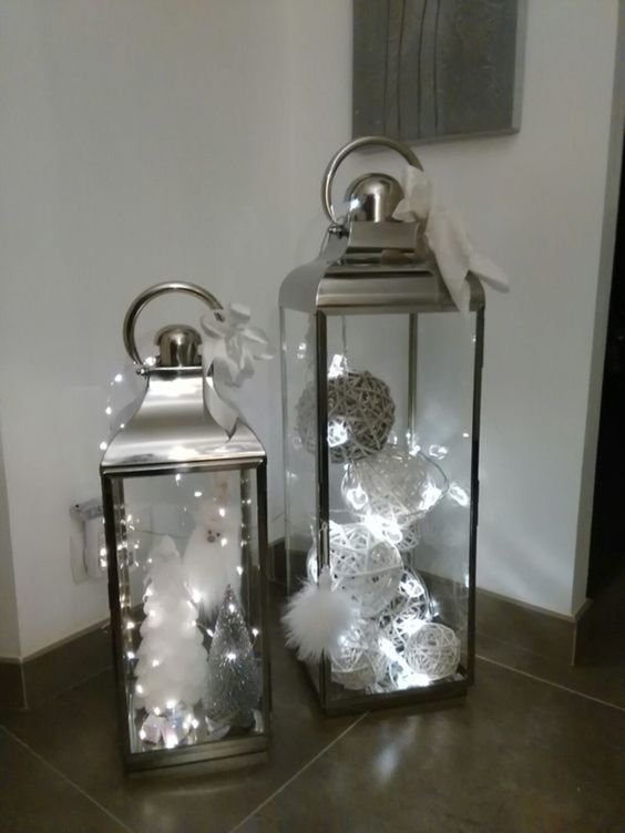 Lanterne natalizie argentate con palline bianche e grigie.
