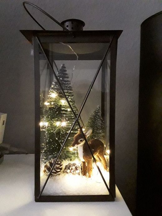 Lanterna natalizia con pigne, capriolo e neve finta.