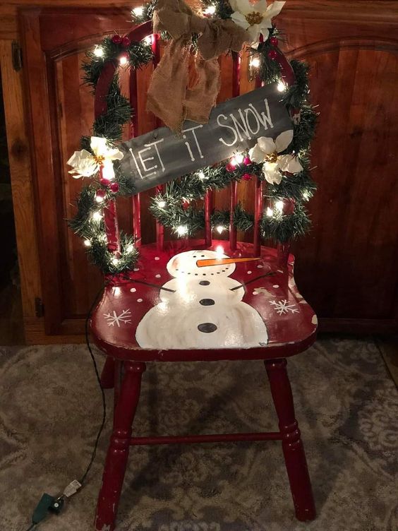 Sedia decorata per Natale con pupazzo di neve pitturato e ghirlanda luminosa.
