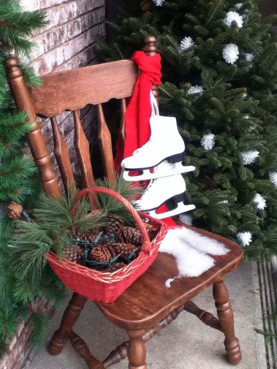 Vecchia sedia in legno decorata con cesto natalizio rosso con pigne e rami di pino.
