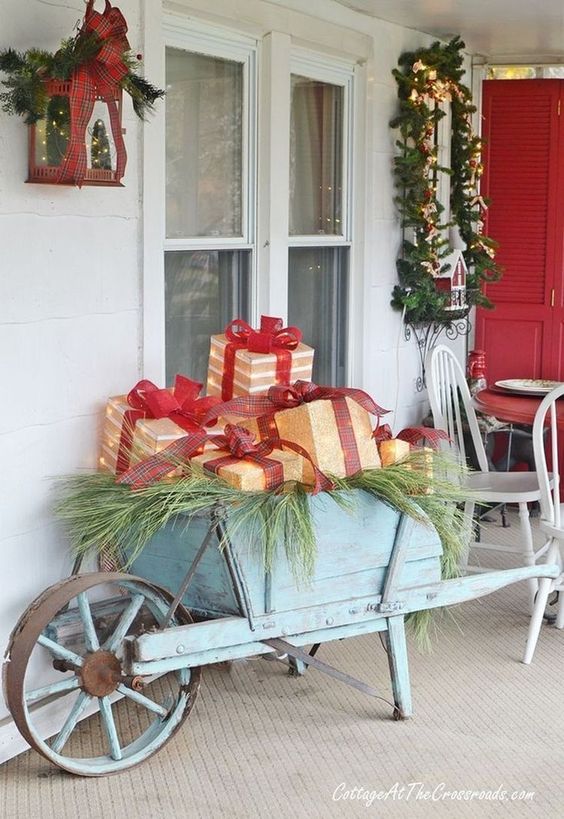 Vecchia carriola in legno con finti regali sotto al portico, decorazione di natale country.