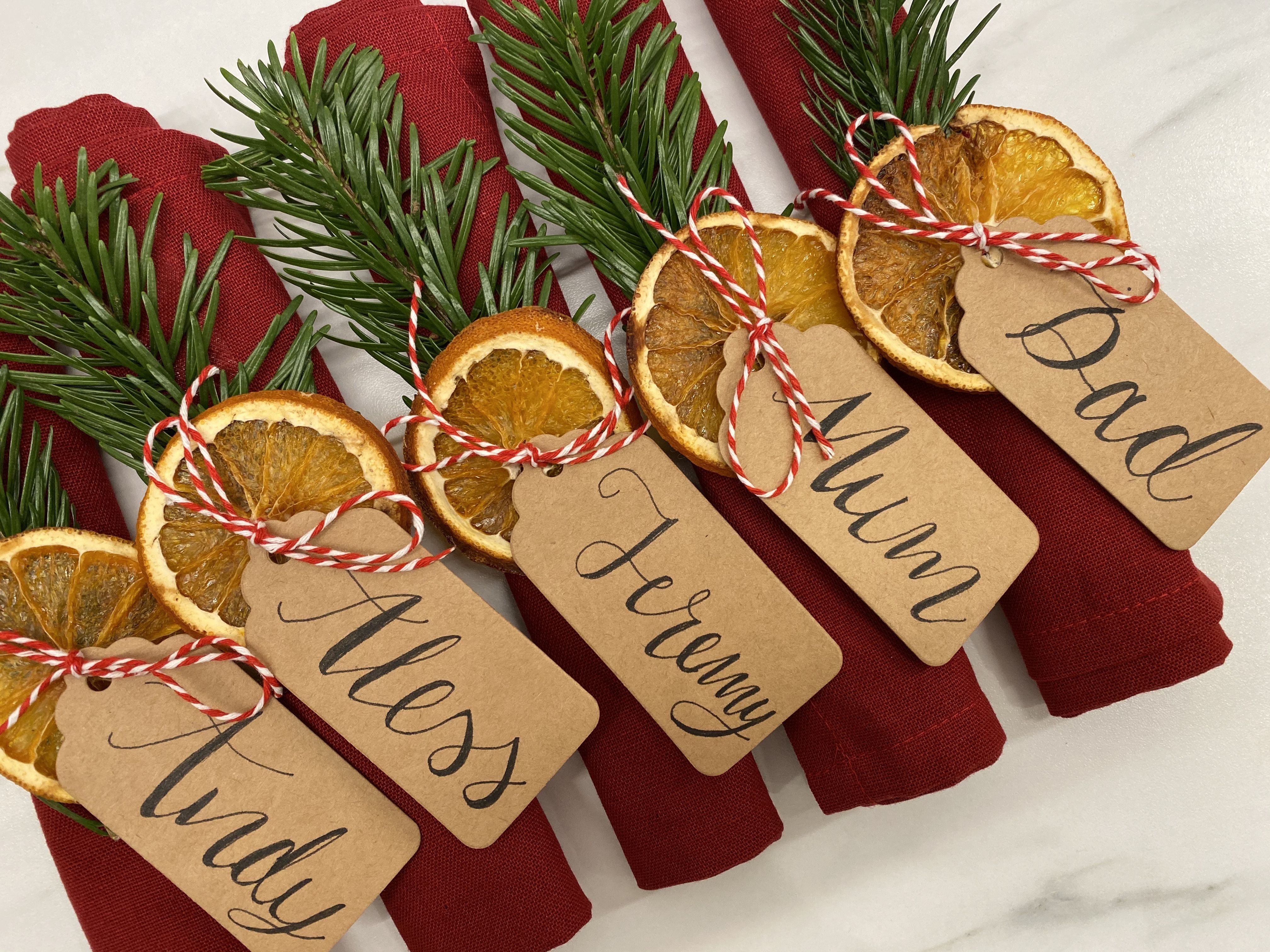 Rami di pino, arancia ed etichetta per segnaposto natalizio.