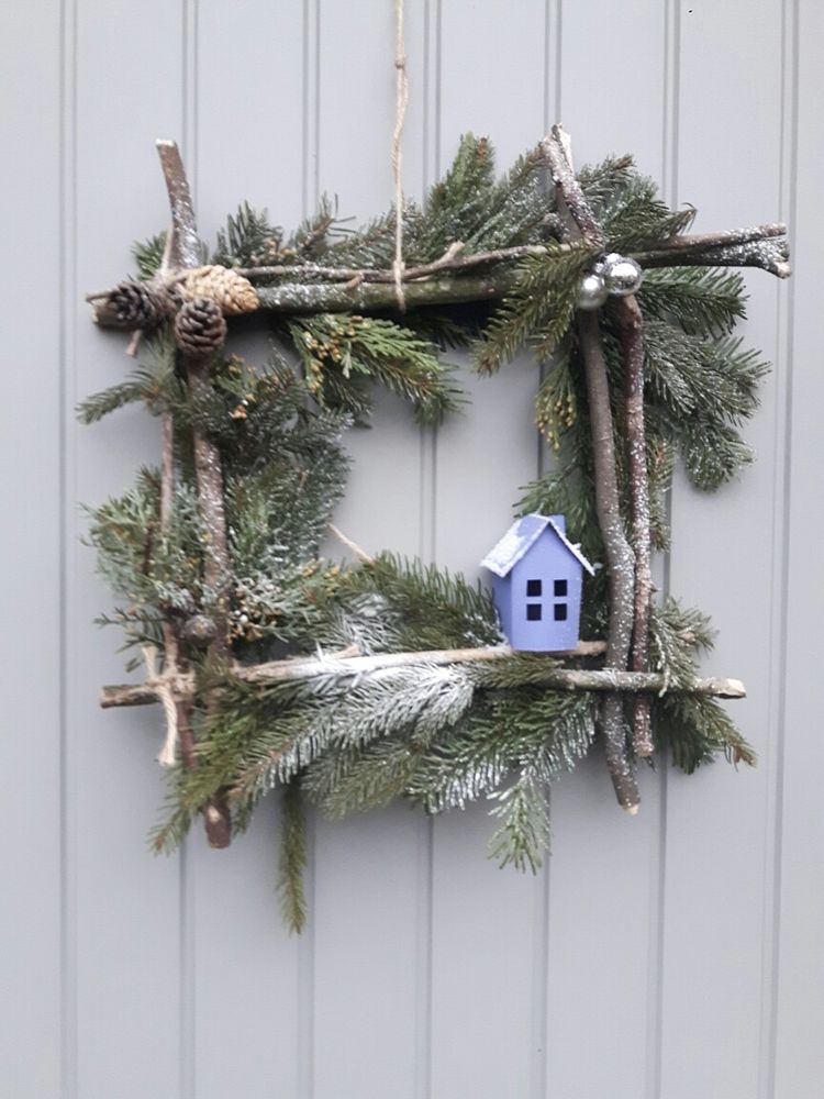 Decorazione natalizia da parete con legnetti e rami di pino.