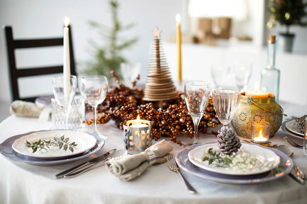 Tavola di capodanno con decorazioni color argento e segnaposto con pigne.