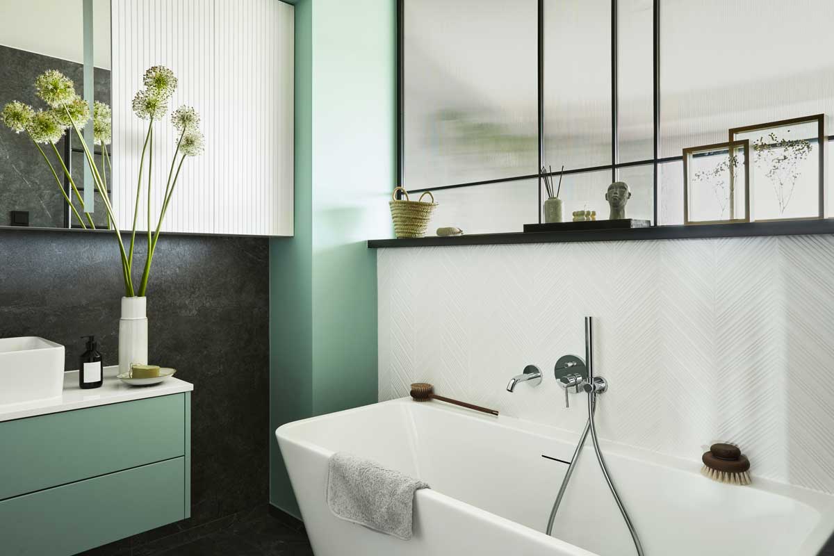 Piccolo bagno con lavabo sospeso e angolo parete colorato.