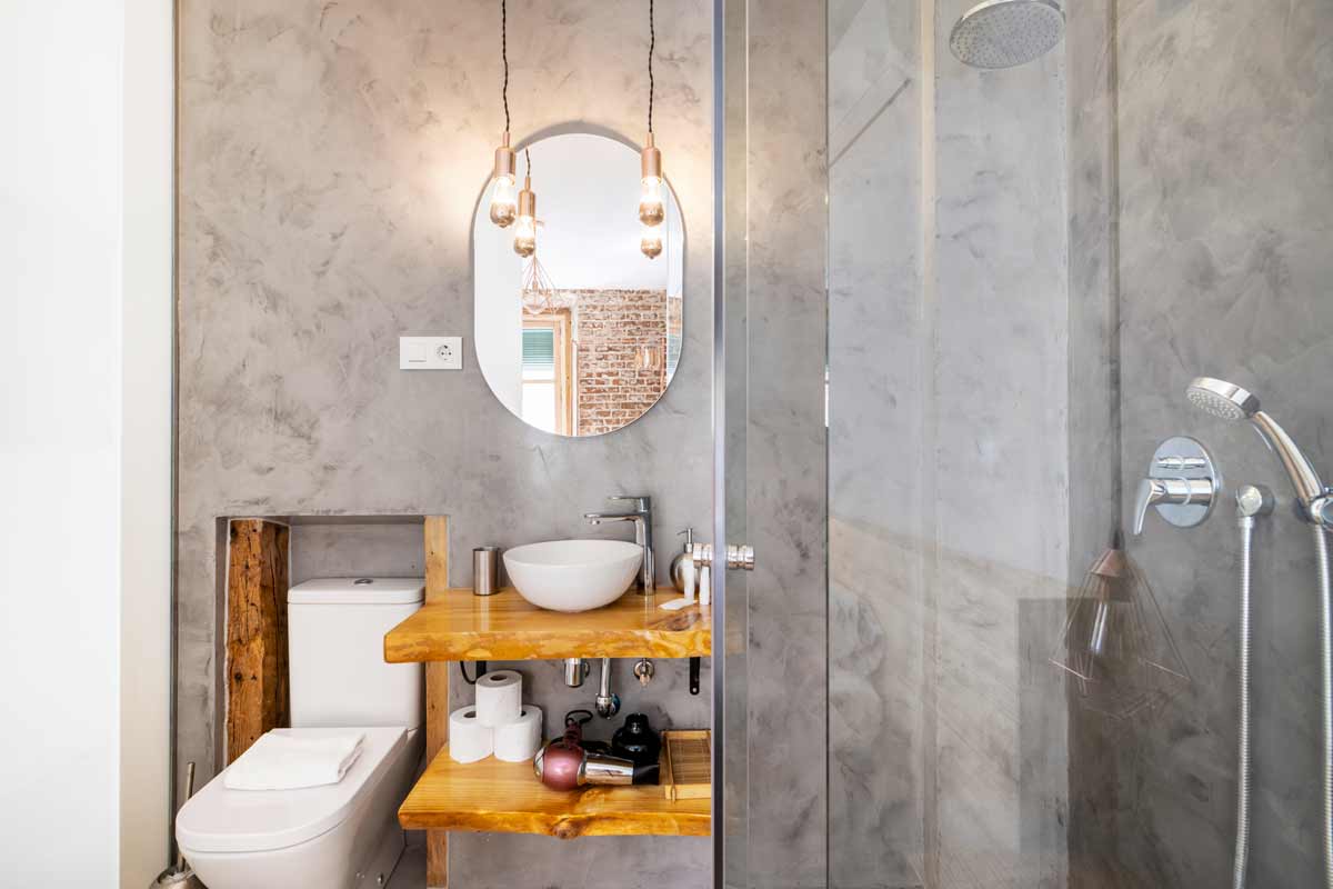 stucco veneziano grigio in un bagno con specchio e mobili in legno chiaro