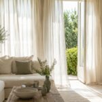 Soggiorno luminoso con tende leggere in lino e luce estiva filtrata