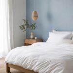 Camera da letto luminosa con parete azzurro polvere e legno chiaro