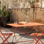 Tavolo Guinguette Maisons du Monde color terracotta apparecchiato su terrazzo estivo