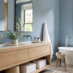 Bagno luminoso con parete blu polvere e mobile in legno chiaro