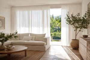 Soggiorno estivo luminoso con tende filtranti bianche davanti alla finestra