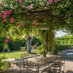 Pergola estiva con rampicanti fioriti che creano ombra naturale in giardino