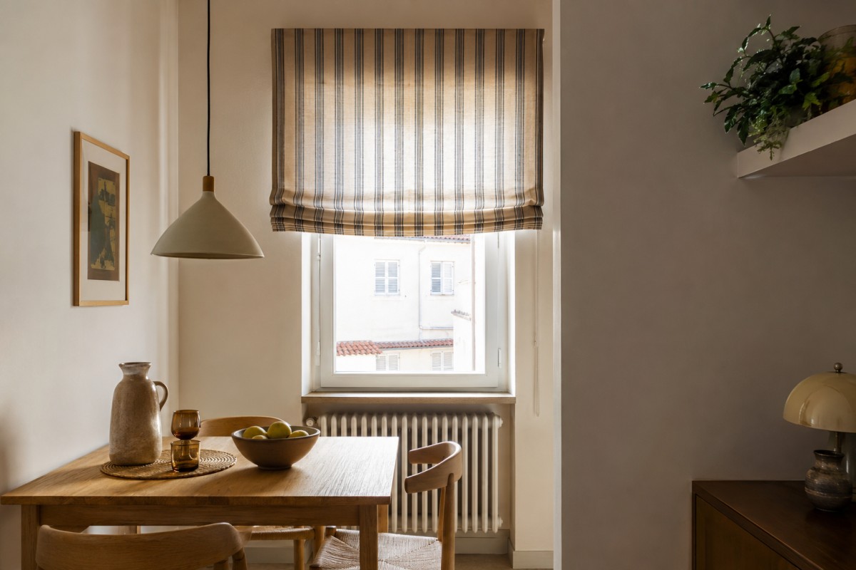 Zona pranzo con tenda a righe e arredo caldo minimale
