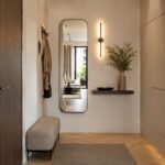 Ingresso stretto arredato con specchio alto mensola sottile e luce calda