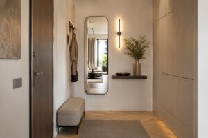 Ingresso stretto arredato con specchio alto mensola sottile e luce calda