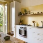 Cucina piccola luminosa con parete giallo burro pensili chiari e legno naturale