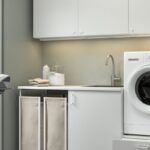 Lavanderia IKEA ENHET con lavatrice rialzata su base bianca e contenitori ordinati