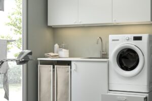 Lavanderia IKEA ENHET con lavatrice rialzata su base bianca e contenitori ordinati