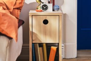 Comodino IKEA PS 2026 in pino accanto al letto con libri e piccoli oggetti