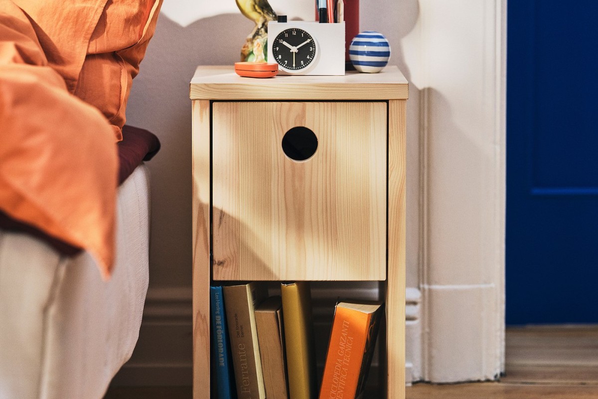 Comodino IKEA PS 2026 in pino accanto al letto con libri e piccoli oggetti