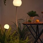Lampada solare IKEA SOLVINDEN accesa tra piante e tavolino da balcone