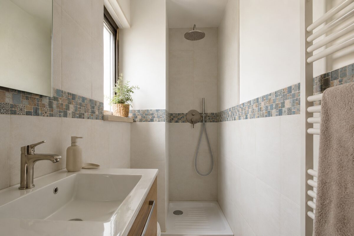 Bagno piccolo con fascia di mosaico ceramico nella zona doccia